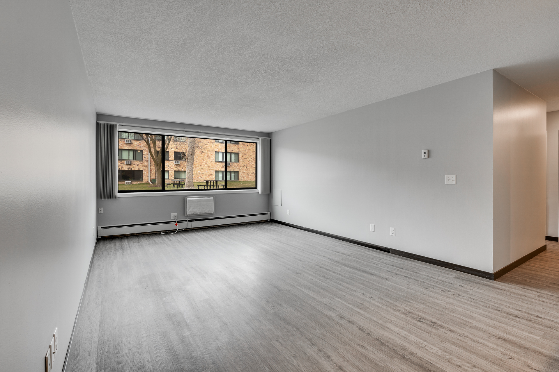 Empty living room with a wall of windows looking out on the grassy commons